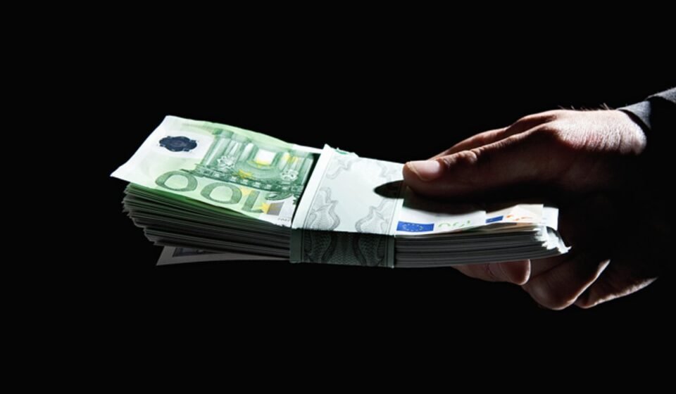 Abschaffung des Bargelds – Der stille Wandel, der alles verändert Hand überreicht ein Bündel 100-Euro-Scheine im Dunkeln – Diskussion um Abschaffung des Bargelds und Anonymität